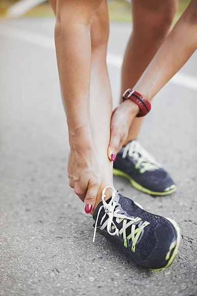 runner-holding-ankle-on-road